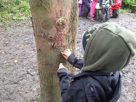 A child makes a clay model attached to a tree